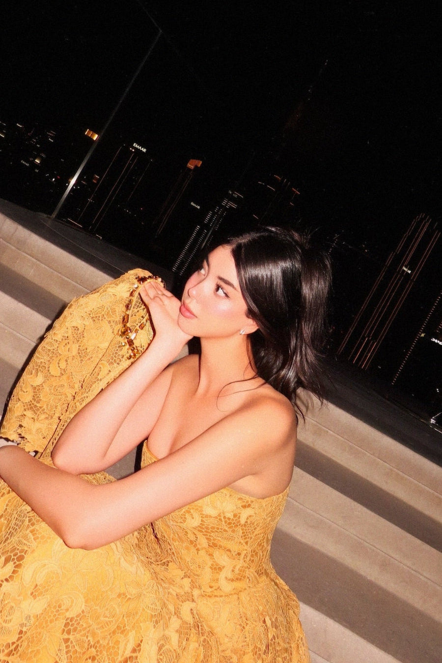 Woman in a yellow dress standing on steps at night.